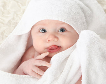 Load image into Gallery viewer, A baby wrapped in an organic bamboo baby towel with hood from Wise Towl
