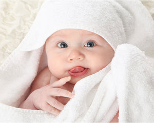 A baby wrapped in an organic bamboo baby towel with hood from Wise Towl